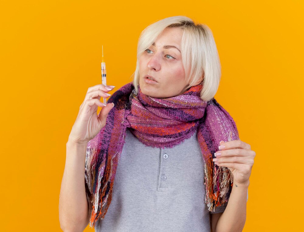 Pale young blonde ill slavic woman wearing scarf holds syringe
